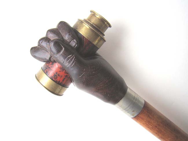 A 20th century Walking Stick featuring a carved 'clenched fist' knob holding a small telescope